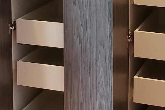 Storage pantry wall with roll-out drawers featuring a waterfall grain slab door design