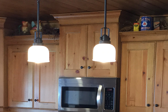 Custom turned legs on kitchen island with bracket base design done in knotty pine with push-pull staggered upper cabinets. Laminated cut-back counter top
