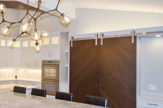 New kitchen install featuring sliding barn door pantry with stainless steel track. Quartz counter top